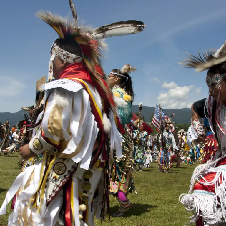 Een dansende groep First Nations, dragen traditionele kleding en hoofddeksels