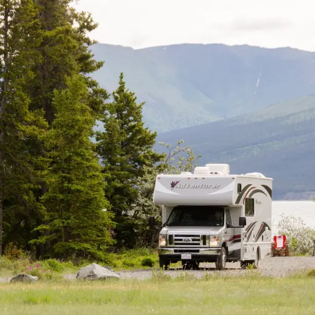 Wohnmobil in grüner bergiger Landschaft an einem See