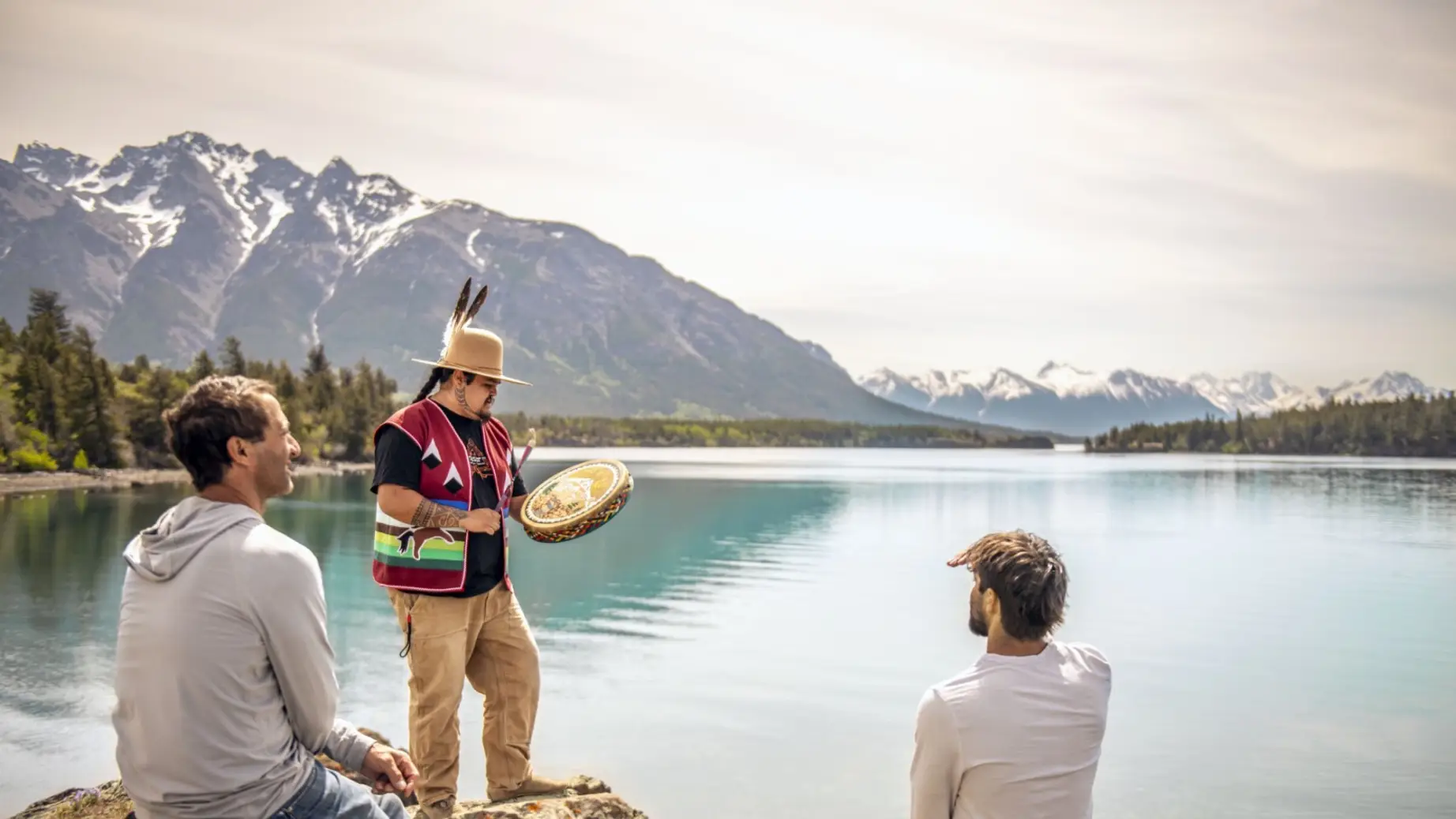 Ein Vater und sein Sohn beobachten eine Trommelzeremonie, die von einem indigenen Führer am Chilko Lake in British Columbia, Kanada, durchgeführt wird.