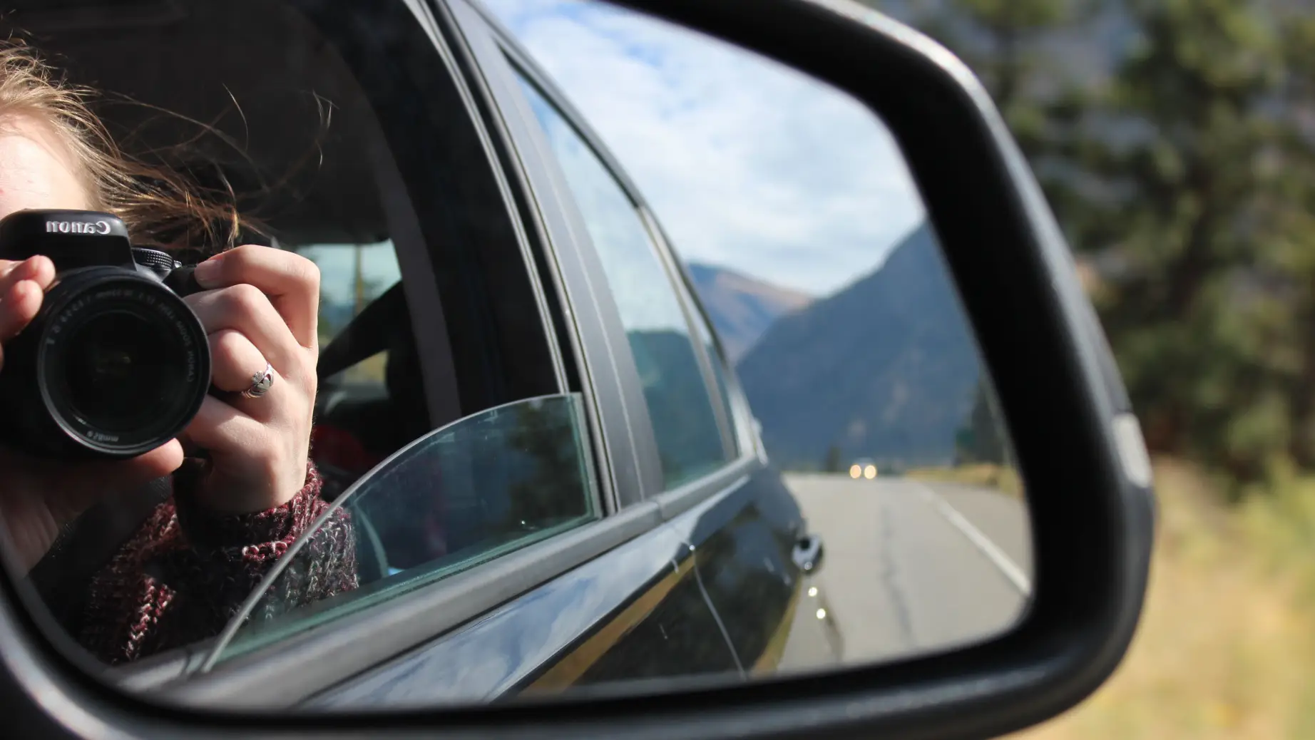 A lady takes a photo from a car window in the Okanagan Valley, Canada