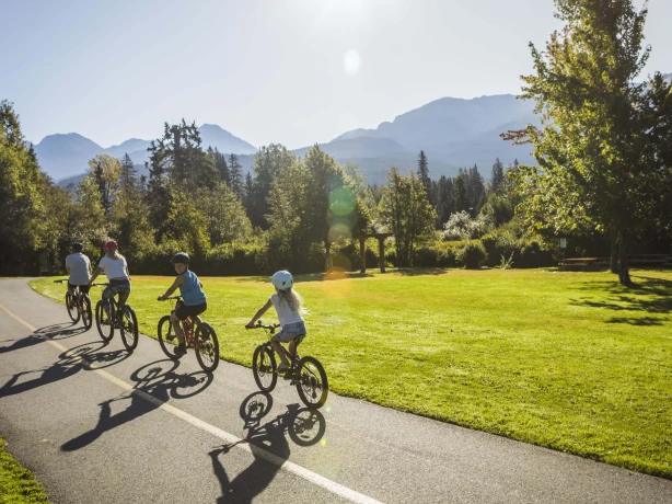 Familie fährt Fahrrad in Kanada mit Bergen im Hintergrund