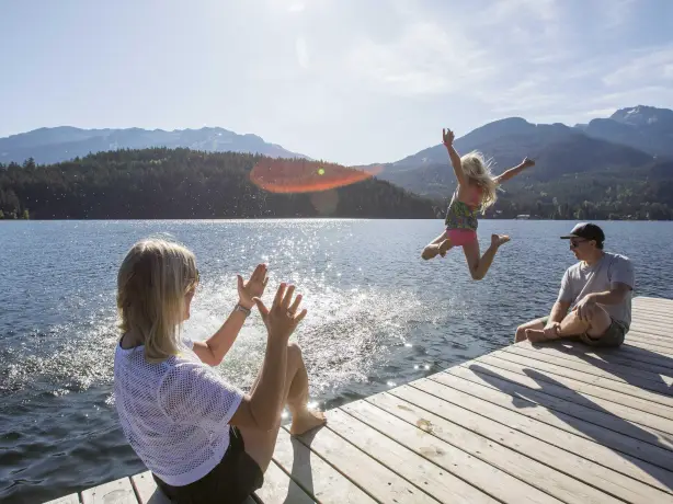 Eine Familie spielt auf einem Steg am Wasser an einem ruhigen See in Kanada
