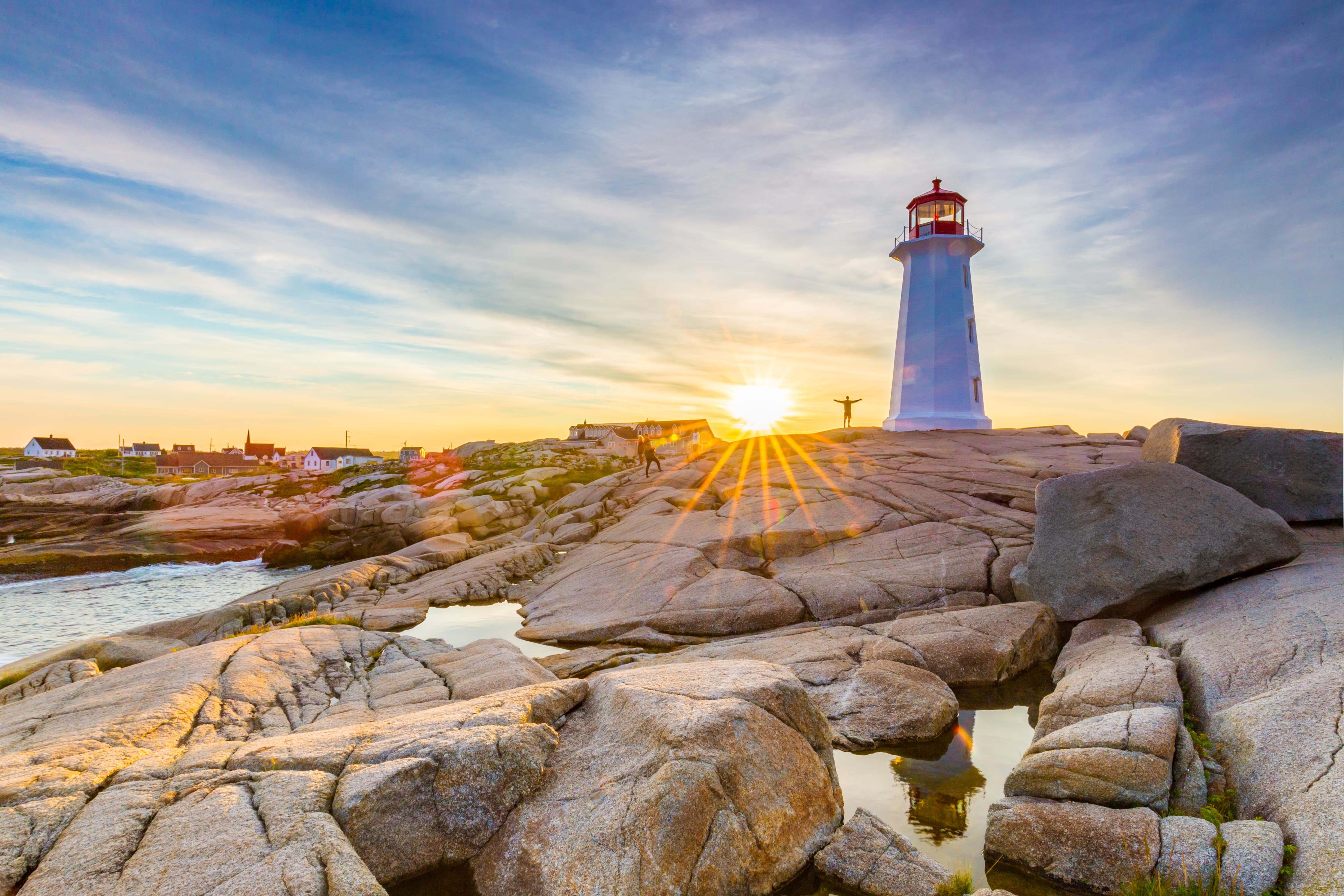 In Peggy’s Cove an der Atlantikküste Kanadas thront ein Leuchtturm auf den Felsen, während die Sonne hinter ihm untergeht
