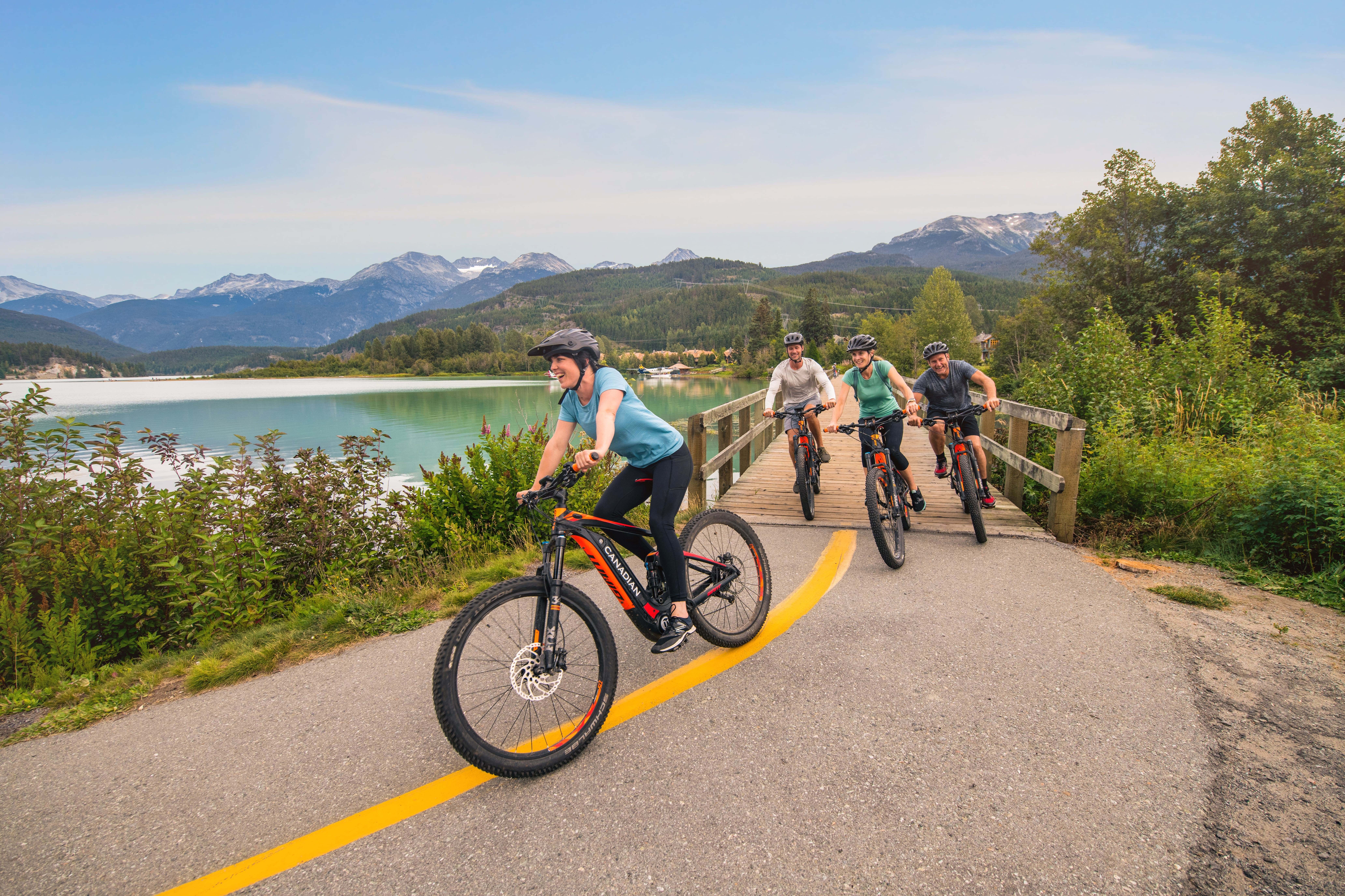 Eine Gruppe, die in Whistler vor der Kulisse von Seen, Wäldern und Bergen Rad fährt
