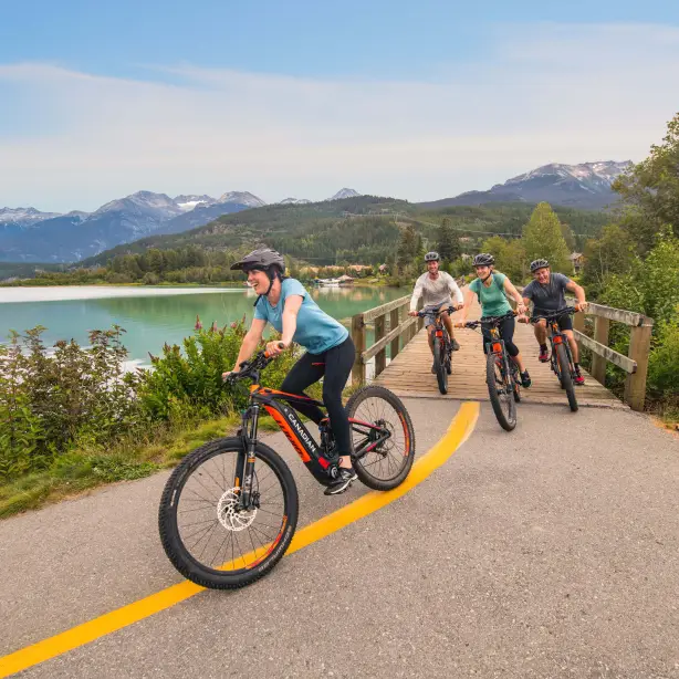 A group cycling around Whistler with a backdrop of lakes, forests and mountains