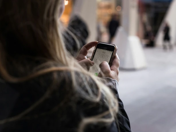 Frau tippt Zahlen auf Handy ein