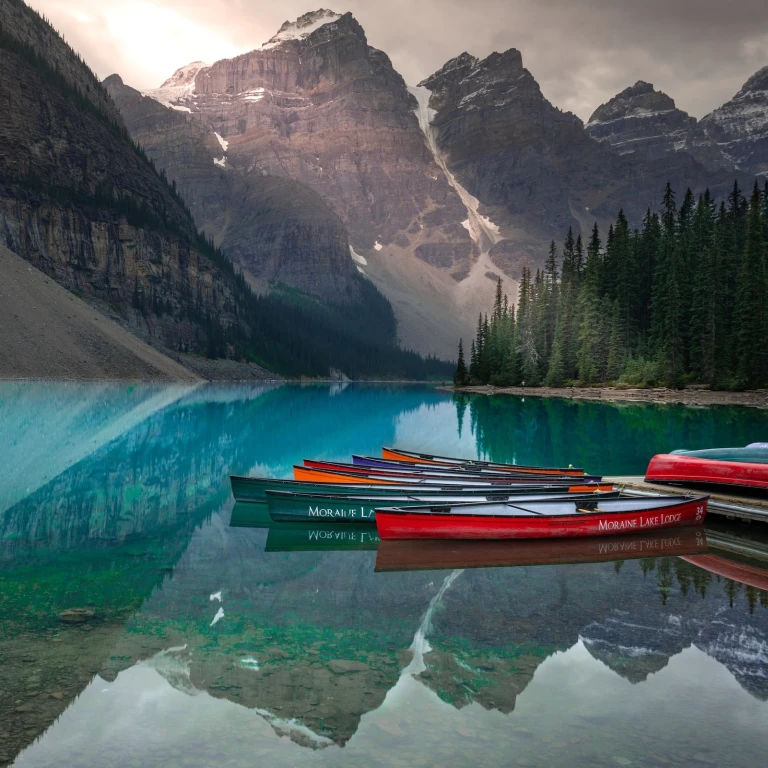 Canoes sit moored by a deck on Moraine Lake in Jasper National Park, Canada, where the surrounding mountains reflect in the water