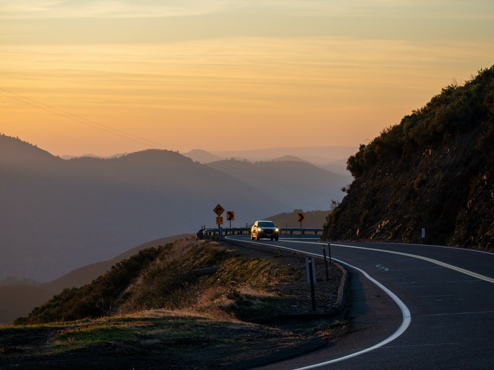 Ein Auto fährt bei Sonnenuntergang durch den Yosemite-Nationalpark, Kalifornien, USA.