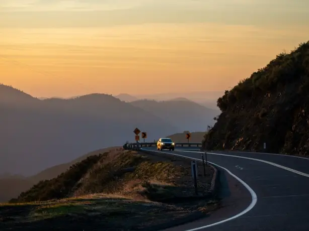 Ein Auto fährt bei Sonnenuntergang durch den Yosemite-Nationalpark, Kalifornien, USA.