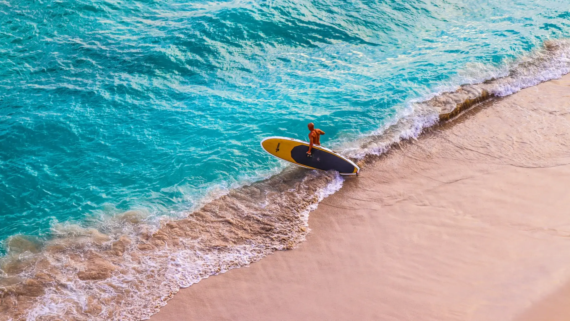 A paddleboarder enters the sea at Wakiki Beach in Hawaii