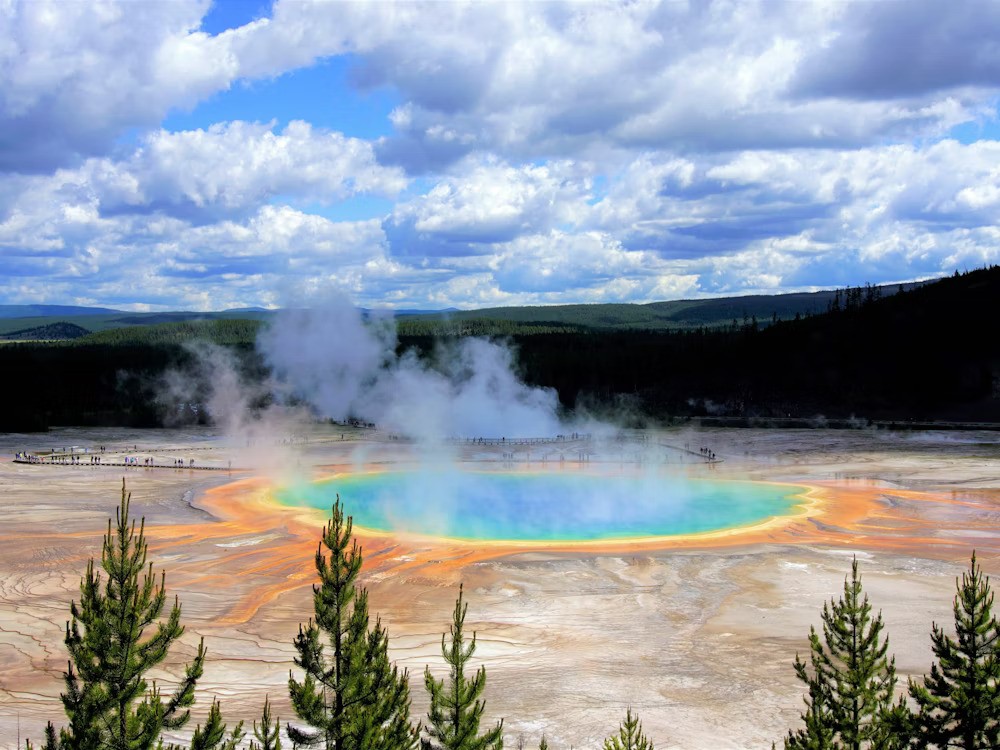 Old Faithful Geyser steaming in Yellowstone National Park with colours of blue, green, orange and yellow