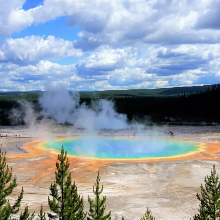 Old Faithful Geyser steaming in Yellowstone National Park with colours of blue, green, orange and yellow