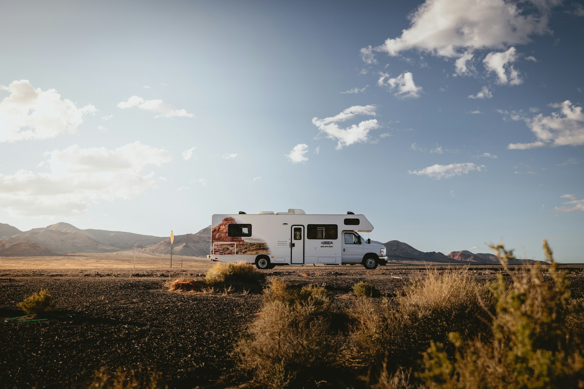 Camper in wüstenartiger Landschaft mit Hügeln im Hintergrund