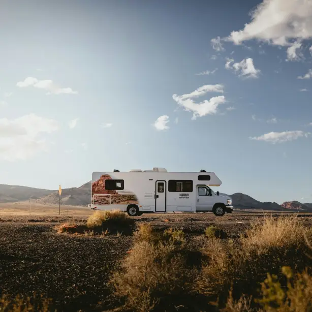 Camper in wüstenartiger Landschaft mit Hügeln im Hintergrund