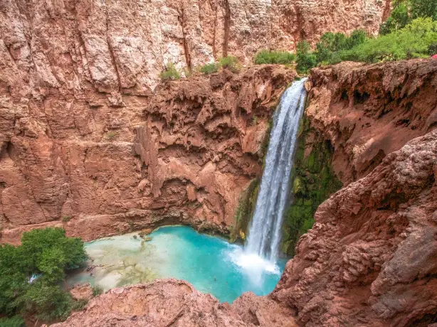 Havasu Falls stützt in türkisblaues Naturbecken, umgeben von roten Felswänden im Grand Canyon