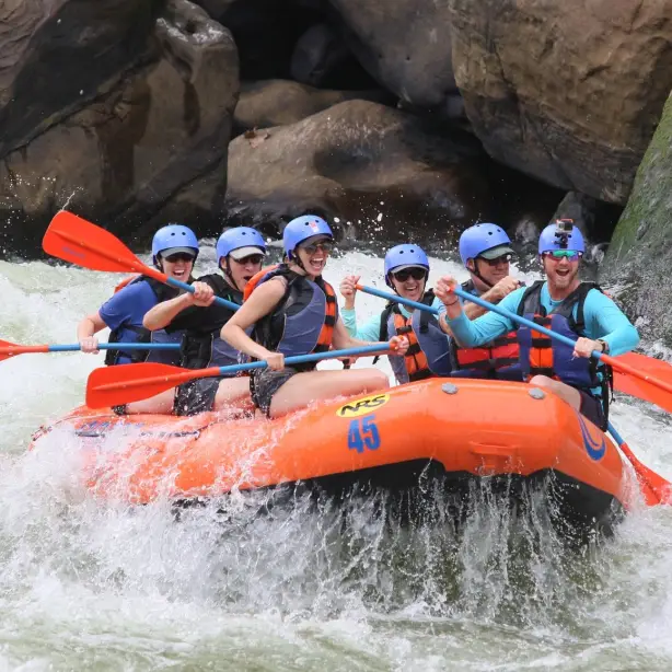 Groep mensen met blauwe helmen raft in een oranje boot door een rivier in Yellowstone National Park