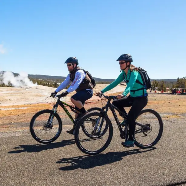 Twee mensen fietsen langs een dampende geiser in Yellowstone National Park, VS