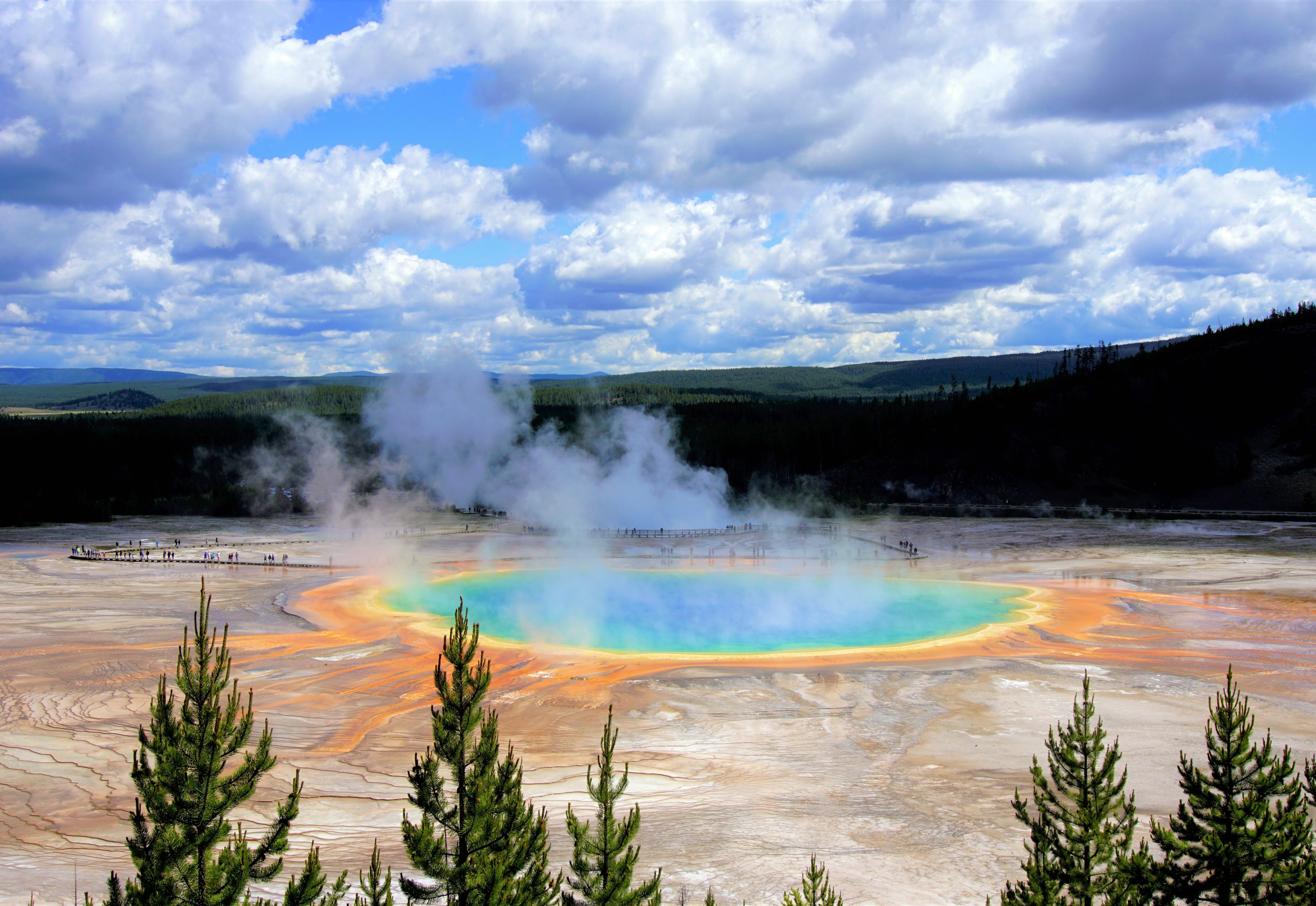 A steaming geyser with blue, green, yellow and orange colours in Yellowstone National Park, USA