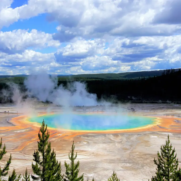 A steaming geyser with blue, green, yellow and orange colours in Yellowstone National Park, USA