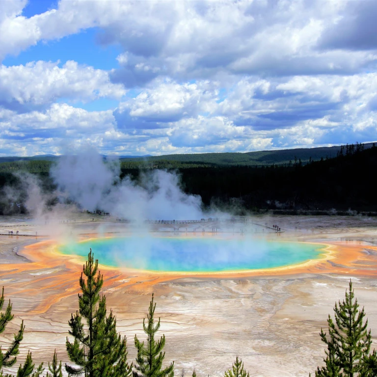 A steaming geyser with blue, green, yellow and orange colours in Yellowstone National Park, USA