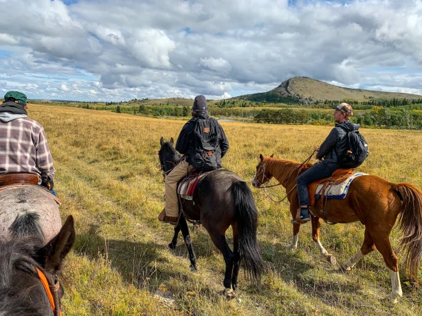 Mitglieder der Blackfeet Nation nehmen einen Touristen mit auf ein Reitabenteuer durch die Landschaften von Montana, USA.