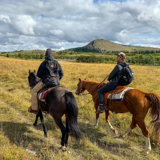 Mitglieder der Blackfeet Nation nehmen einen Touristen mit auf ein Reitabenteuer durch die Landschaften von Montana, USA.
