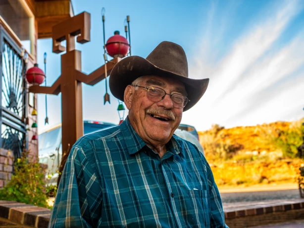 Älterer Amerikaner mit Cowboyhut und Brille lacht