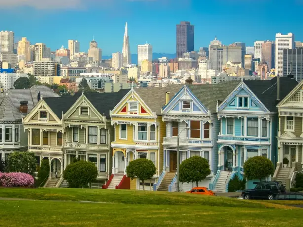 Berühmten Painted Ladies in San Francisco vor einer grünen Parkwiese vor der Skyline