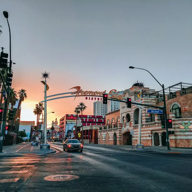 Auto rijdt door Fremont East in Las Vegas met een kleurrijke zonsondergang op de achtergrond