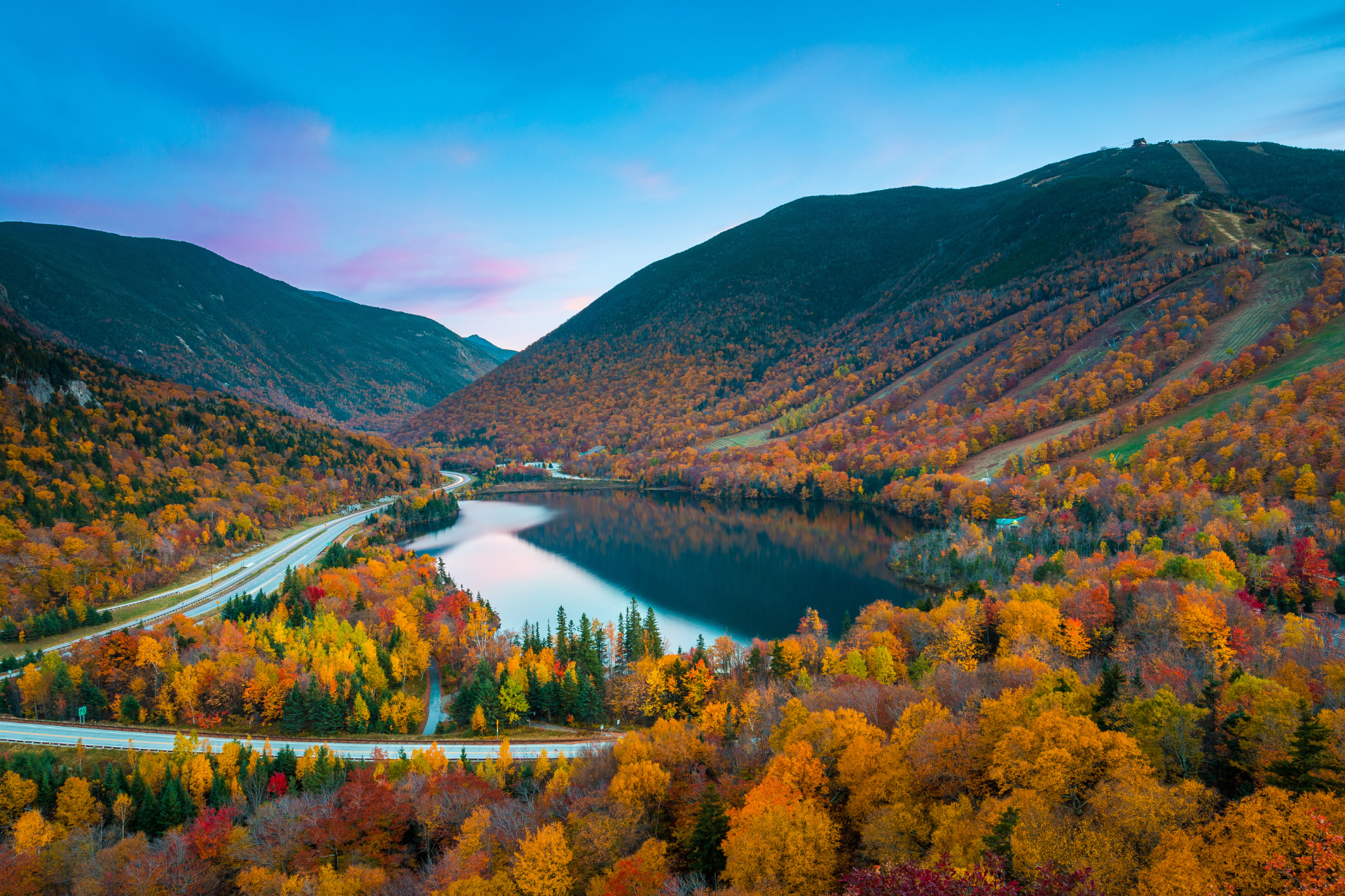 Herbstlaub rund um einen See und eine Straße in New England, USA