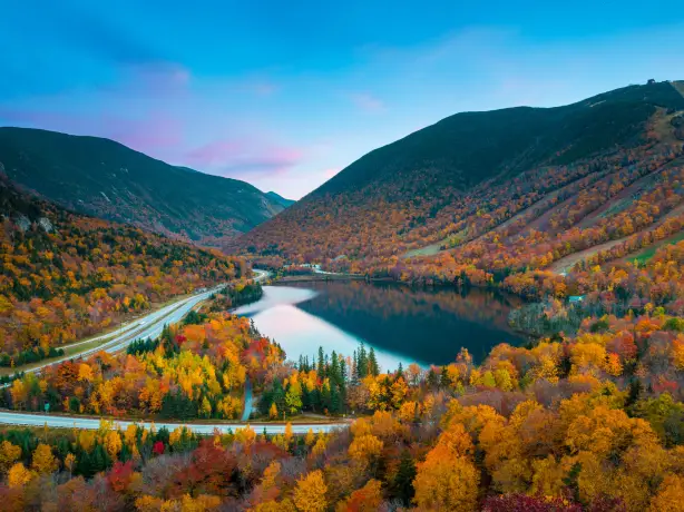 Herbstlaub rund um einen See und eine Straße in New England, USA