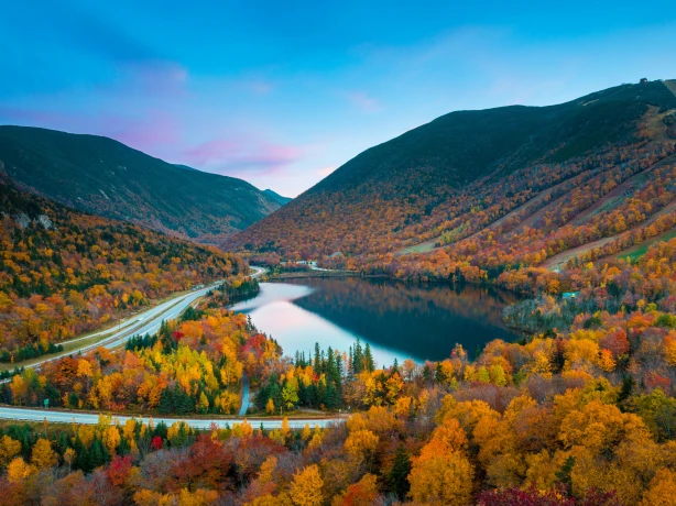 Herbstlaub rund um einen See und eine Straße in New England, USA