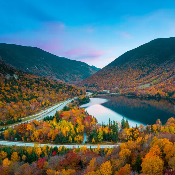 Herbstlaub rund um einen See und eine Straße in New England, USA
