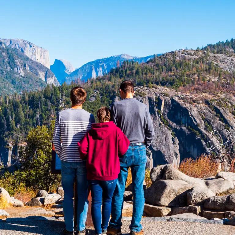 Drie jonge mensen kijken uit over het gebergte van Yosemite National Park