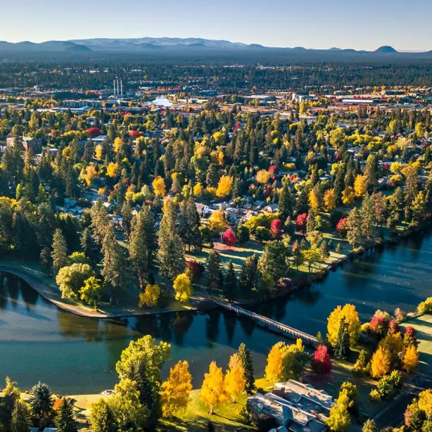 Een luchtfoto van het groene Drake Park met de Deschutes River op de voorgrond in Bend