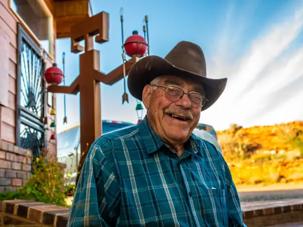 Älterer Amerikaner mit Cowboyhut und Brille lacht