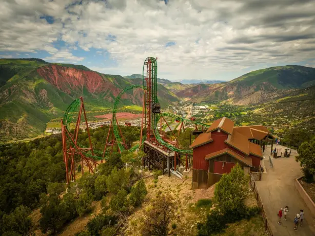 Achterbahn im Glenwood Caverns Adventure Park hoch über Glenwood Springs in Colorado. Im Hintergrund erstrecken sich die bewaldeten Berge und das Tal des Colorado River.