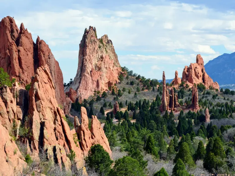 Landschaft mit großen, säulenartigen roten Felsen inmitten grüner Nadelbäume