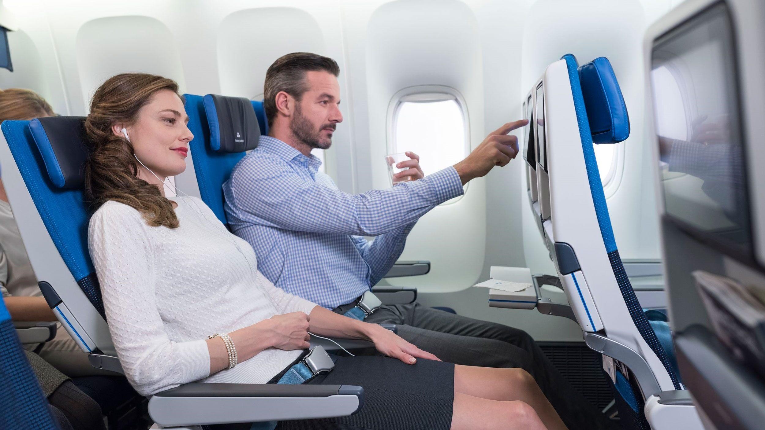 Zwei Personen fliegen in der Premium Economy, eine nutzt das Bordunterhaltungssystem