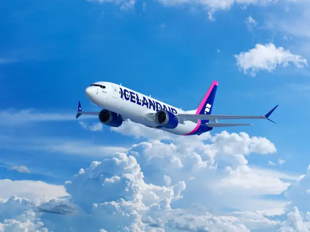 Ein Flugzeug der Icelandair fliegt über strahlend weißen Wolken vor einem klaren blauen Himmel.