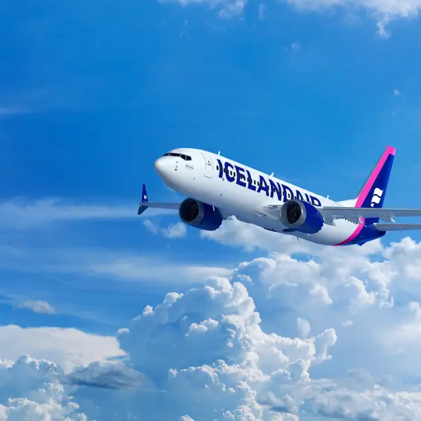Ein Flugzeug der Icelandair fliegt über strahlend weißen Wolken vor einem klaren blauen Himmel.