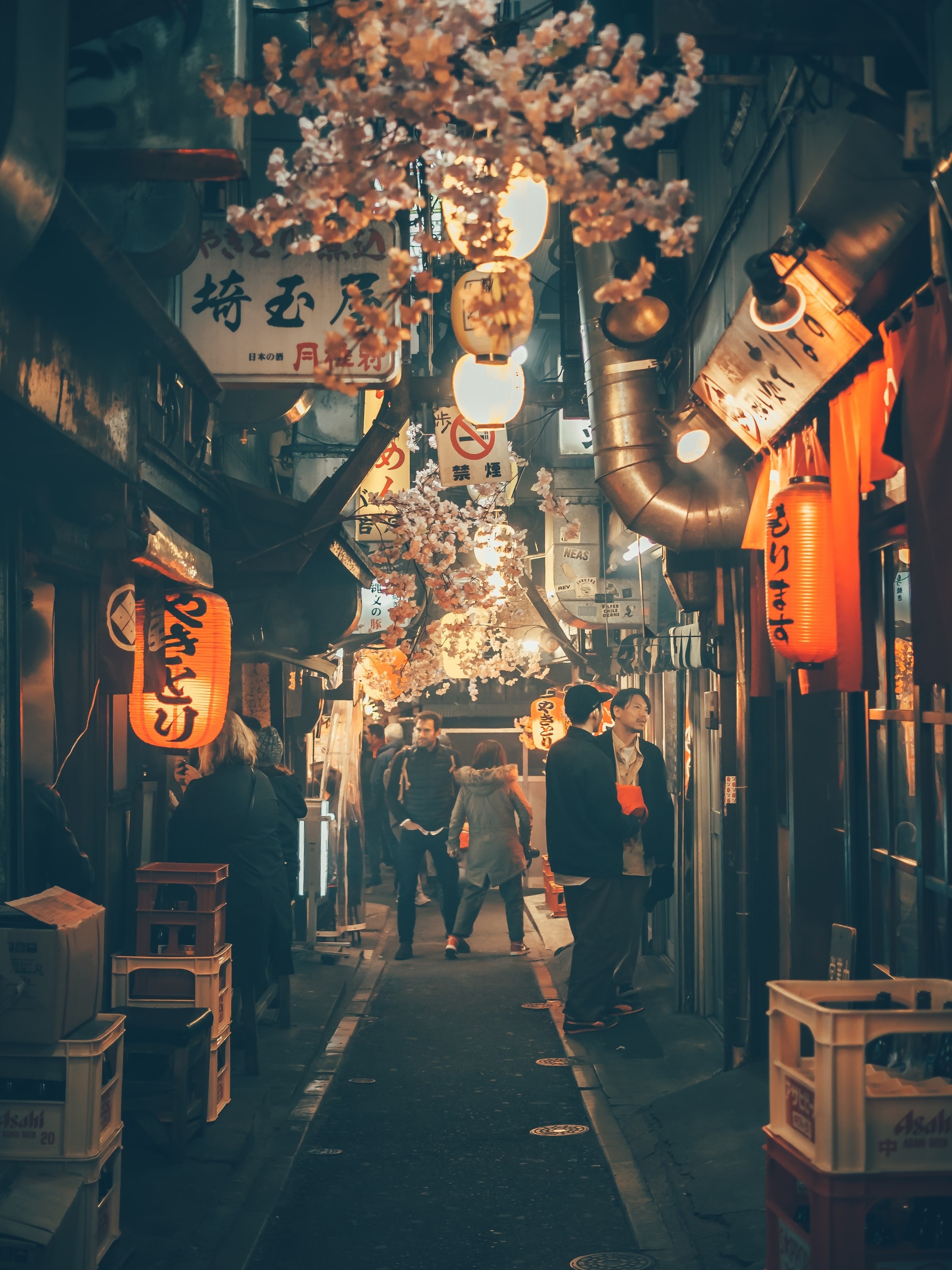 Mensen lopen door een smalle straat in Tokio verlicht met lantaarns