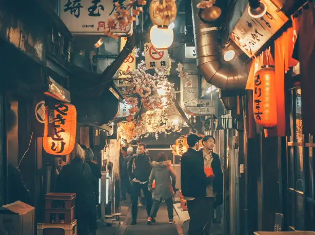 Mensen lopen door een smalle straat in Tokio verlicht met lantaarns