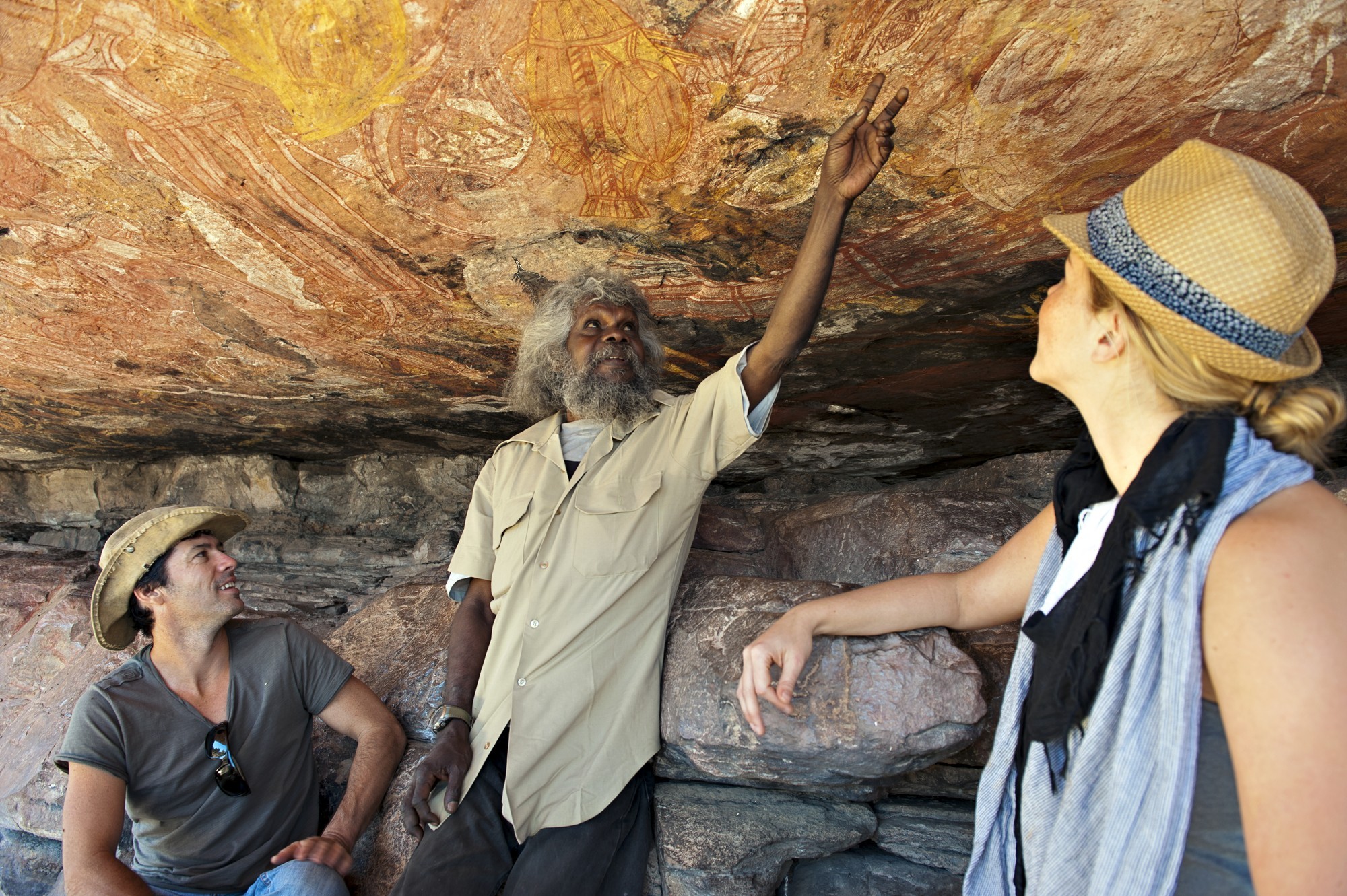 A local Aboriginal guide showing a pair of tourists ancient rock art in Australia