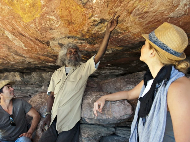 A local Aboriginal guide showing a pair of tourists ancient rock art in Australia