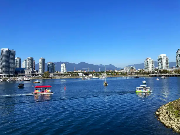 Bunter Aquabus fährt über das Wasser mit Skyline von Vancouver und Berge im Hintergrund