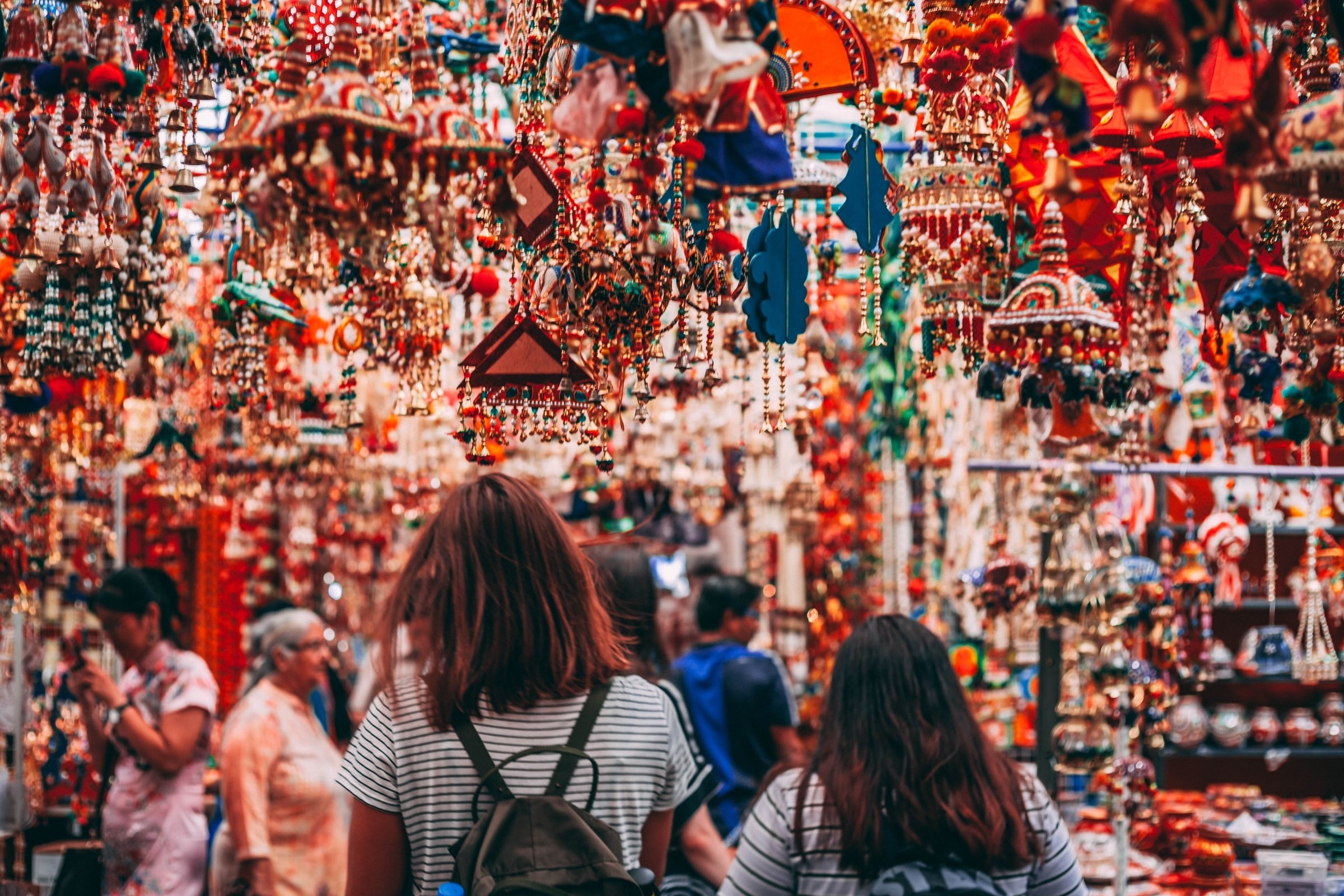 Two women seen from behind at a colourful market in Singapore