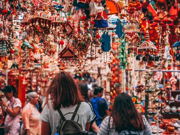 Two women seen from behind at a colourful market in Singapore