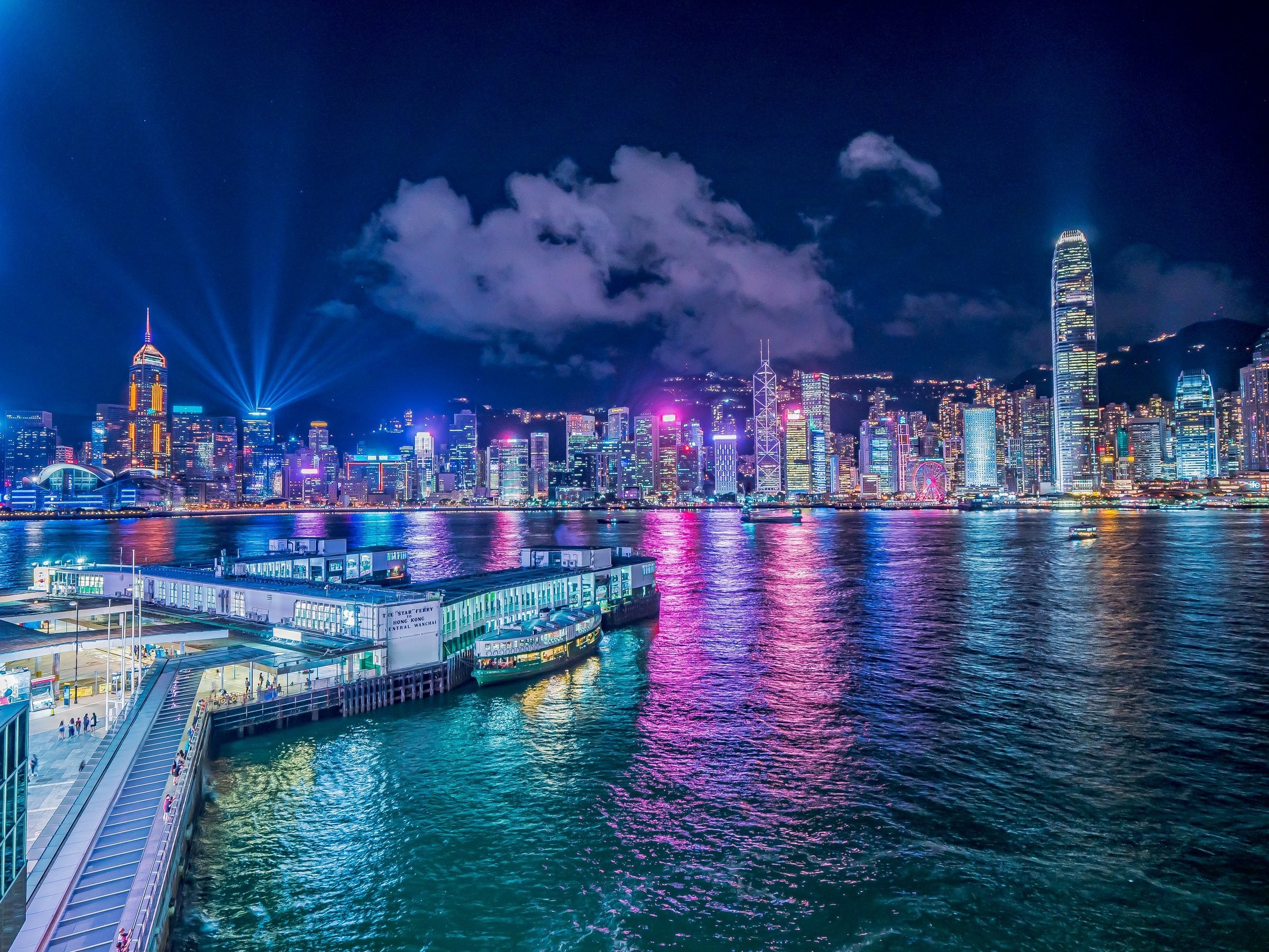 Zicht op de helder verlichte stad 's nachts, kleuren weerspiegelen in het water in Hong-Kong