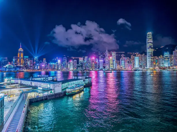 Zicht op de helder verlichte stad 's nachts, kleuren weerspiegelen in het water in Hong-Kong